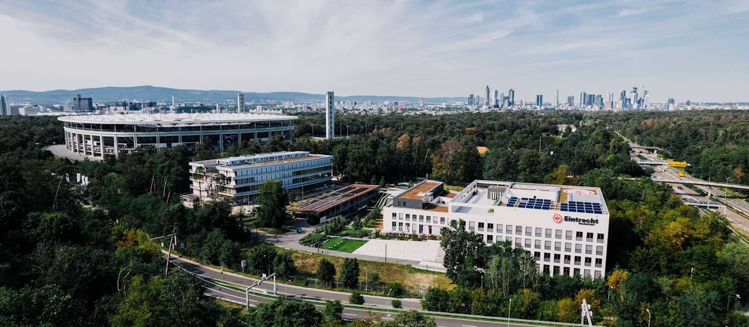 Eintracht Frankfurt Gästefan-Infos mit Blick auf den Deutsche Bank Park und Skyline von Frankfurt im Hintergrund