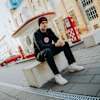 Sitzend, schräg von links: Mann mit schwarzer Eintracht Frankfurt Mütze und schwarzem Pullover mit SGE-Logo sitzt auf einem Stein.