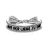 Vorderseite: Ein schwarz-weißes Eintracht-Armband mit schwarzem Schriftzug "AUS DER LIEBE ZU DIR" und Quasten.