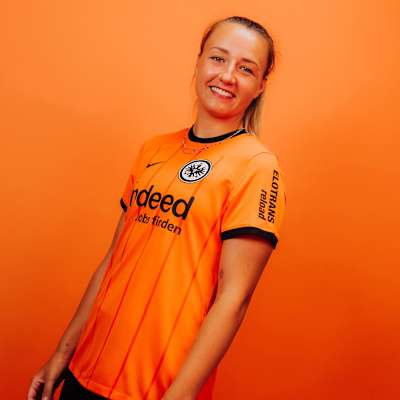 Spielerin im Eintracht Frankfurt Ausweichtrikot 2024/25 in Orange mit schwarzen Details vor orangenem Hintergrund. Damen Trikot Ausweich 24
