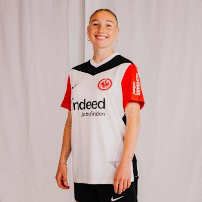 Spielerin im weißen Damen-Heimtrikot 2024/25 von Eintracht Frankfurt mit roten Ärmeln und schwarzem V-Kragen. Damen Trikot Heim 24