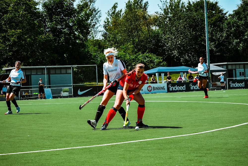 Eine Adlerträgerin kämpft beim Hockey um den Ball.