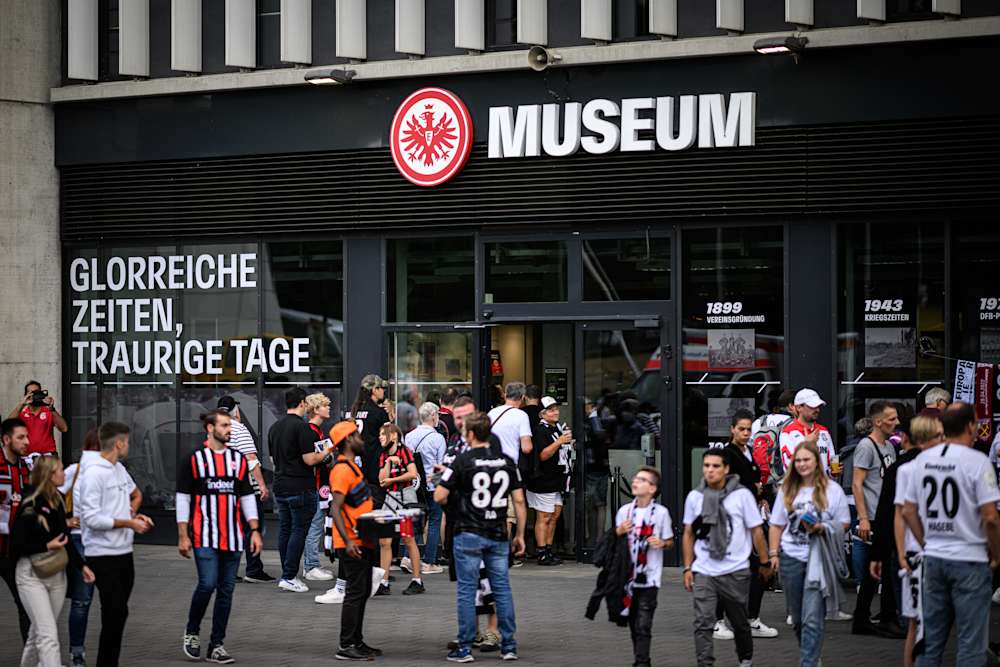 Das Museum geht in eine Sommerpause. Das Bild zeigt Menschen in Eintracht-Trikots vor dem Eingang des Museums.
